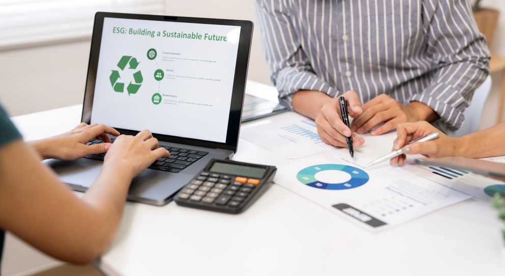 Healthcare professionals reviewing sustainability and ESG performance data on a laptop, with environmental metrics and charts displayed during a procurement planning meeting.